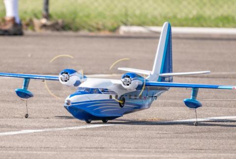 Blue model seaplane on the ground with propellers spinning.