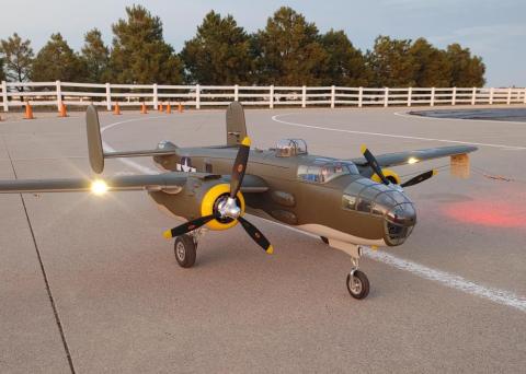 Model aircraft on runway at sunset, lights illuminated.