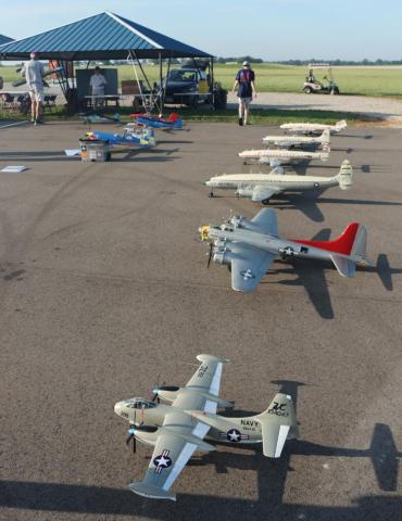 Model airplanes displayed on an airfield with people in the background.