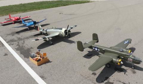 Model aircraft lined up on pavement, including WWII-era planes in varying colors.