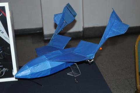 Blue model airplane with twin tails, displayed on a dark surface.