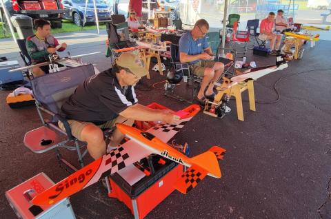 People assembling model airplanes under a tent.