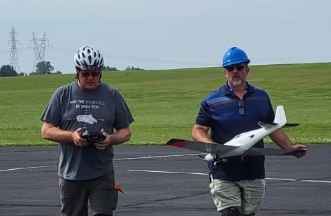After a heat, Bill Hauth checks the settings on his transmitter as teammate Tim Gould walks Bill’s plane off the runway. After a heat, Bill Hauth checks the settings on his transmitter as teammate Tim Gould walks Bill’s plane off the runway.