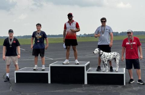 Five people and a Dalmatian on podiums outdoors.
