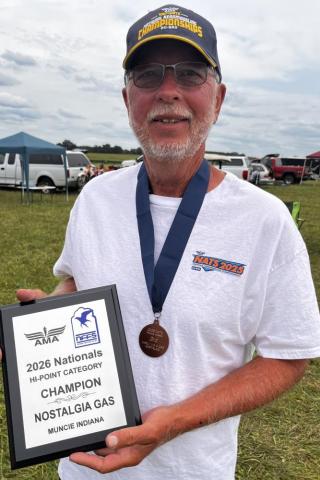 Man holding racing trophy and wearing medal, smiling outdoors.