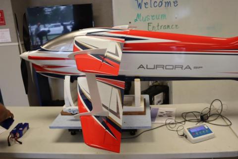 Large red and white model airplane on a table at a museum entrance.
