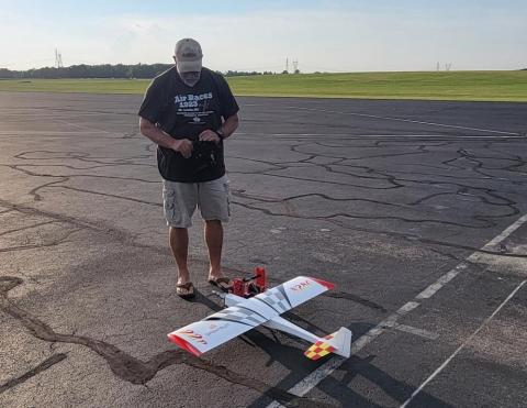 Man preparing a model airplane on an airfield.