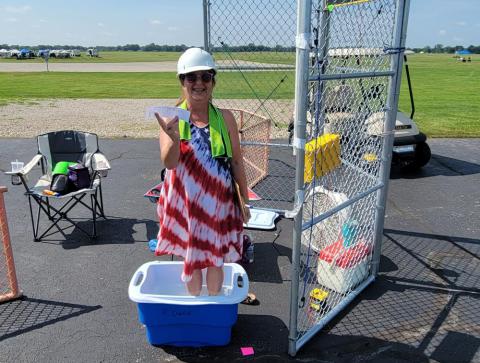 Woman smiling in a tie-dye dress, standing in a cooler at an outdoor event.