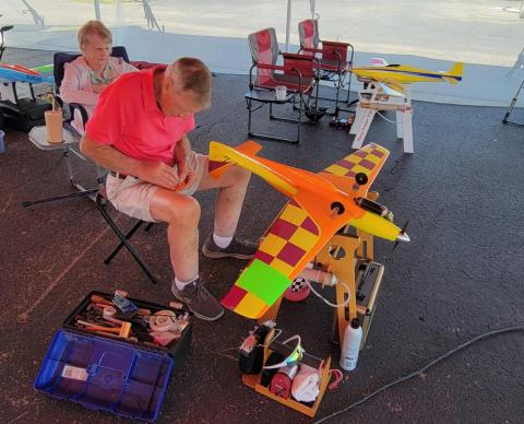 Two people assembling a brightly colored model airplane.