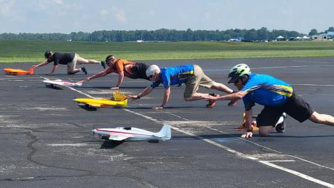 Men on a runway launching colorful model planes.