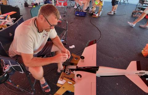 Man assembling a model airplane on a picnic table.