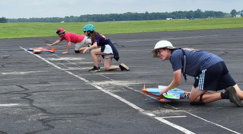 Mitchell Haupt, Tom Doe, and Jack Kane push their pilot’s plane at the start.