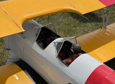 Model biplane with yellow and red wings, featuring two seated pilots.
