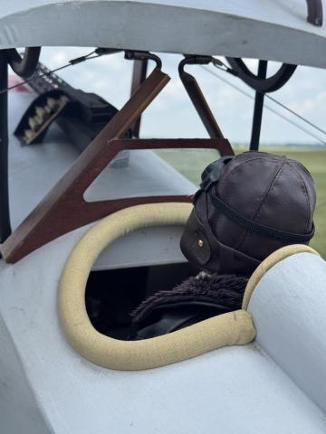 A person wearing a leather aviator cap in a vintage aircraft cockpit.