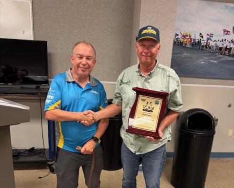 Two men shaking hands, one holding a plaque.