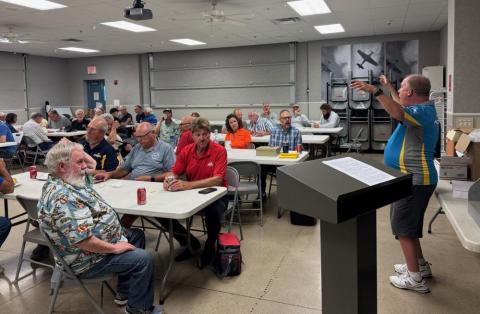 A man speaks to an audience in a classroom setting.
