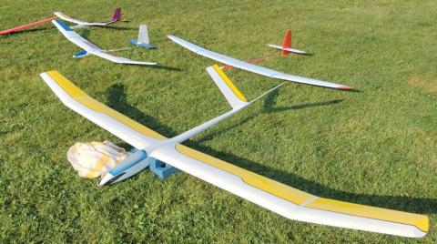 Model gliders with colorful wings on grass field.