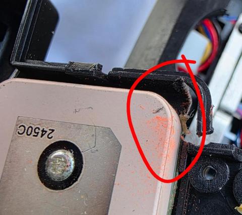Damaged circuit board corner with exposed wires, red circle highlighting the area.