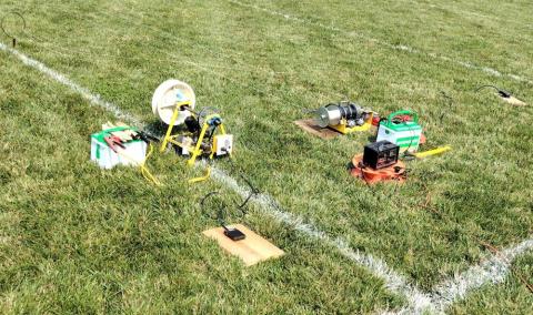 Grass field with electronics and equipment scattered on the ground.