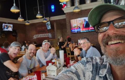 Group of five people smiling at a restaurant table.