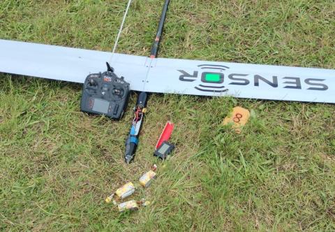 Remote control and model plane parts on grass.