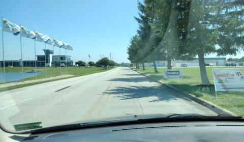 Road flanked by flags and trees on a sunny day.