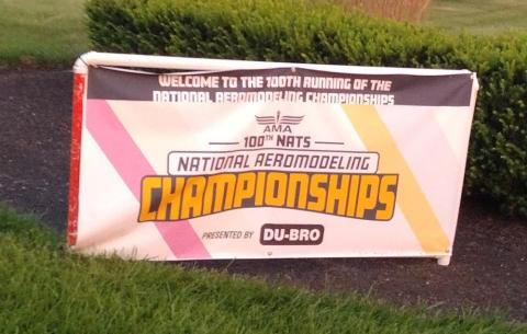 National Aeromodeling Championships banner near bushes.