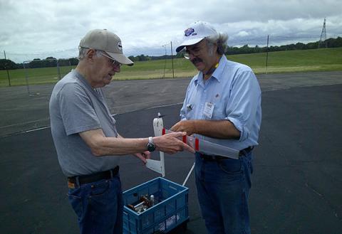 Henry Nelson holds James Van Sant’s ½A Speed plane while Glen Van Sant fuels it for another speed flight.