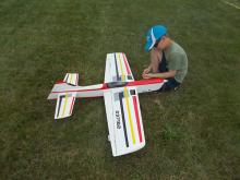 Boy assembling model plane on grass.