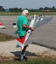 Man holding a large model airplane outdoors.
