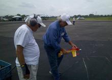 Two men on a tarmac studying chalk markings.