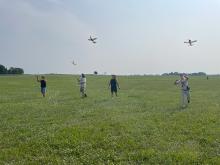 Group flying model airplanes in a field.