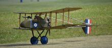 Vintage biplane with blue wheels on grassy field.