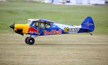 Small propeller plane with Red Bull branding on a grassy field.