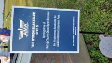 Sign honoring donor Byron Blakeslee at an aeromodeling center, grass in the background.