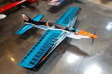 Model airplane with orange, black, and blue design on glossy floor.