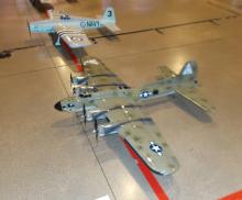 Two model military aircraft on a floor, one labeled "NAVY" in the background.