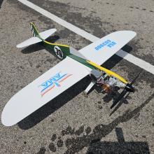 A model airplane with propeller and colorful markings on an asphalt surface.