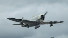 A vintage fighter plane flying in a cloudy sky.
