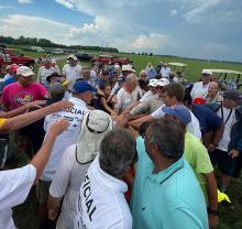 Group of people in a field, hands joined in the center.